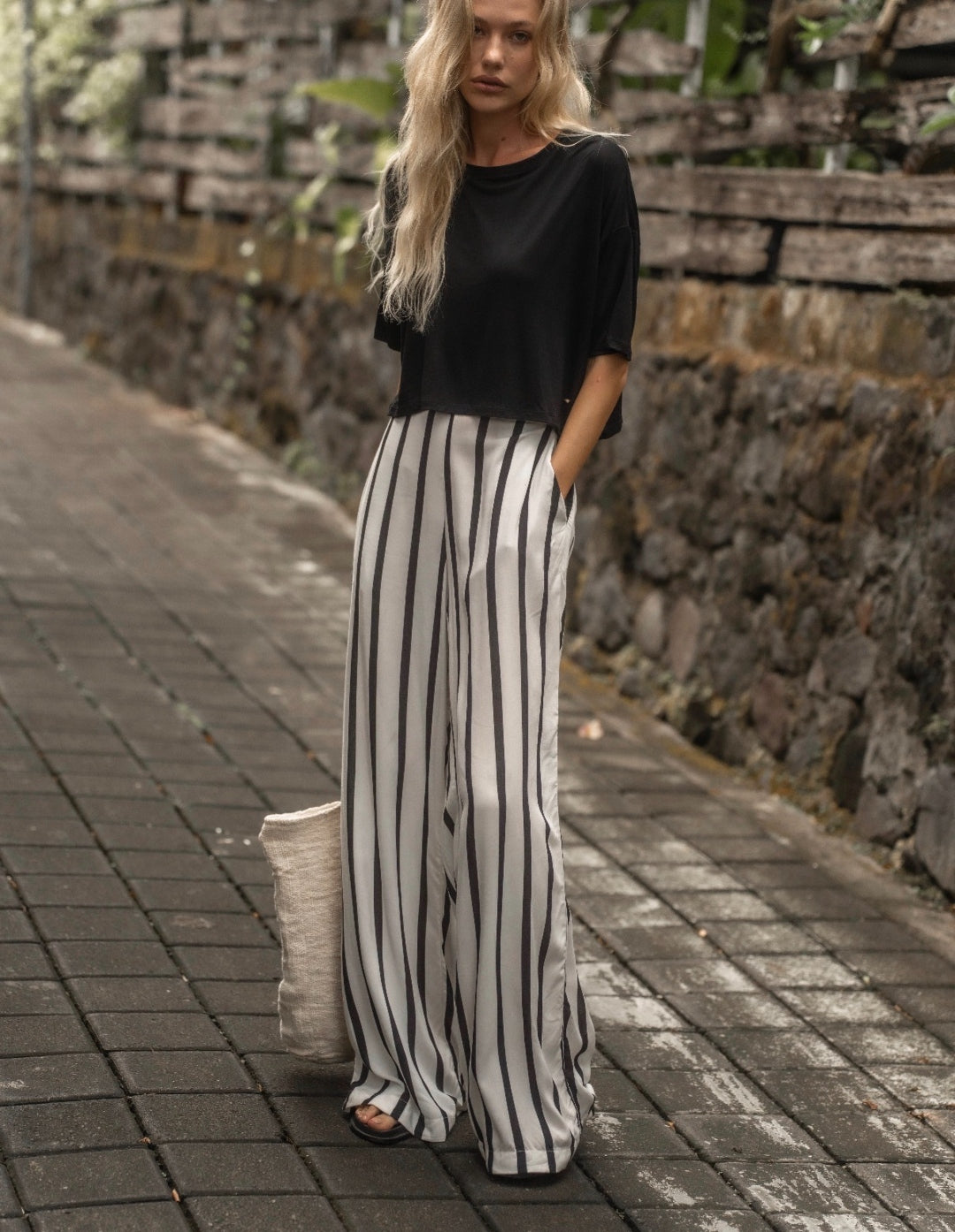 The Travel T in black worn with striped wide-leg pants